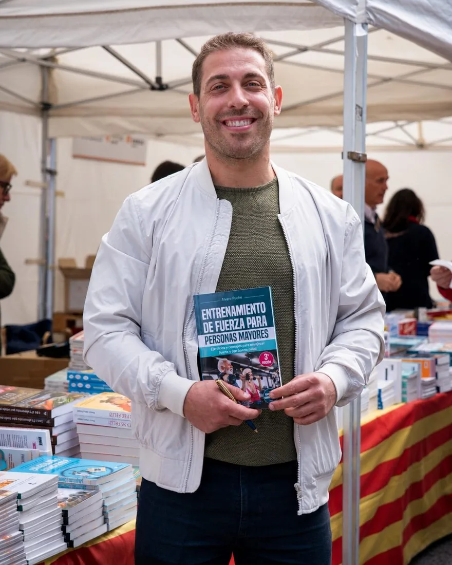 Álvaro Puche firmando ejemplares de Entrenamiento de fuerza para personas mayores en una feria del libro