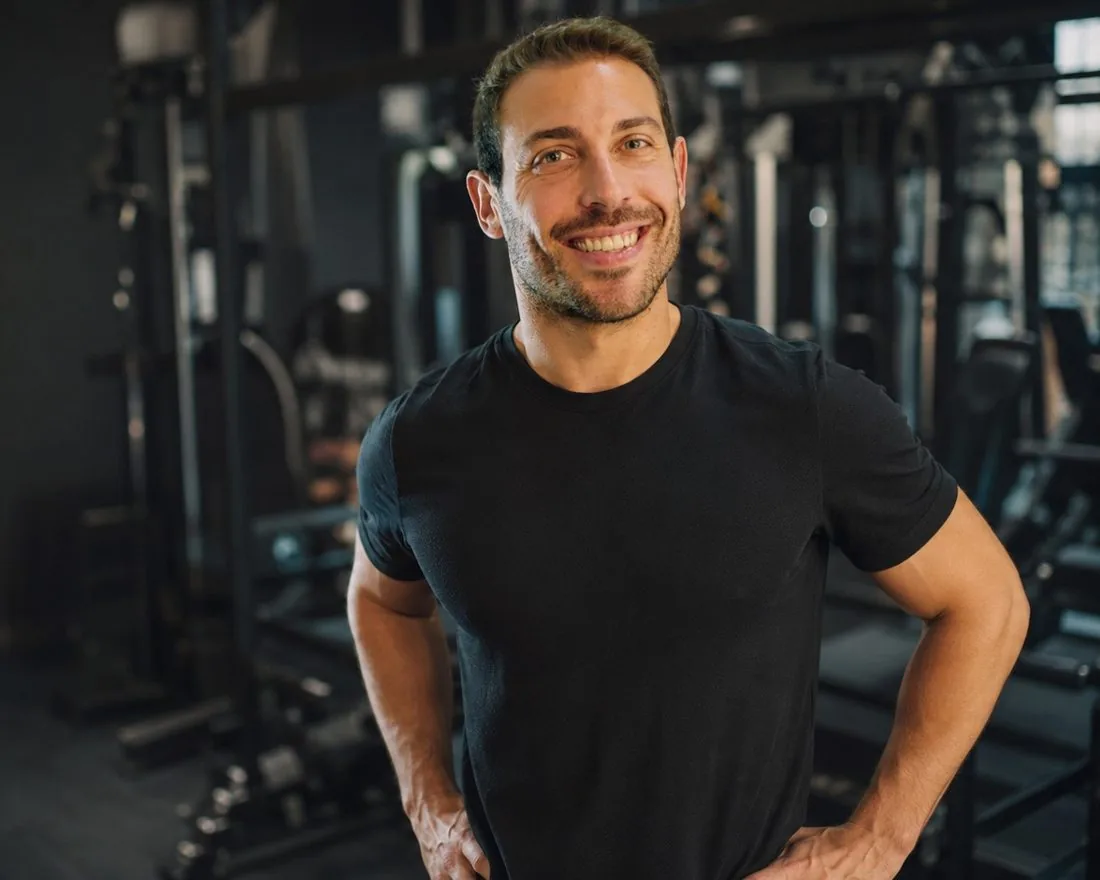 Álvaro Puche en el gimnasio, sonriendo junto a las máquinas de entrenamiento